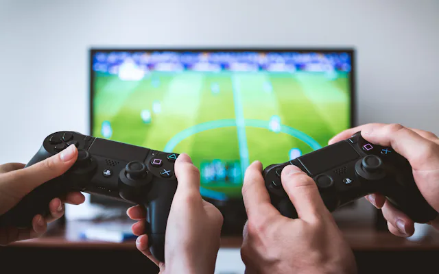 Two friends holding game controllers in front of a TV during a casual gaming session